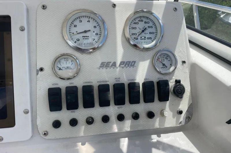 Slide: The Image of Control panel of a 2004 Sea Pro 238 Walk Around boat with gauges and switches. - 13