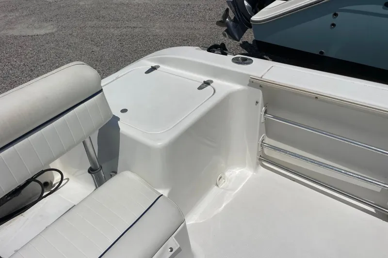 Slide: The Image of 2004 Sea Pro 238 Walk Around boat interior with white seating and storage compartment. - 26