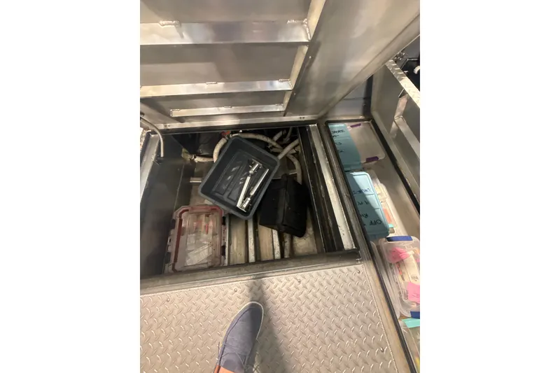 Slide: The Image of Interior storage compartment of 2022 Hewescraft 270 Alaskan Hardtop with tools and containers. - 18