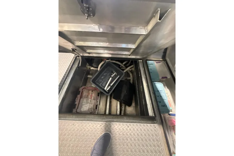 Slide: The Image of Open storage compartment in 2022 Hewescraft 270 Alaskan Hardtop boat, containing tools and equipment. - 19