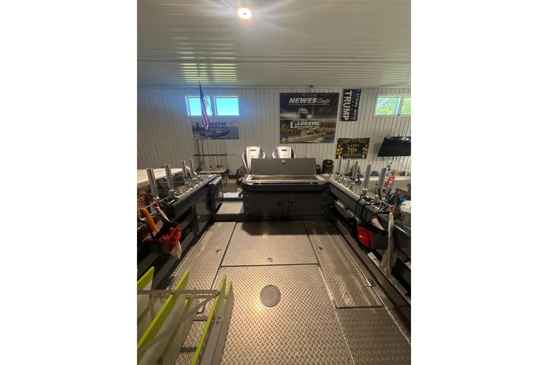 Slide: The Image of 2022 Hewescraft 270 Alaskan Hardtop interior with fishing gear and banners in a garage. - 3
