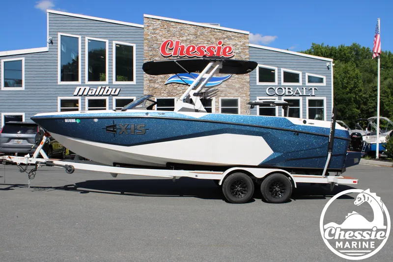 Slide: The Image of A 2025 Axis A245 boat on a trailer in front of a building. - 2