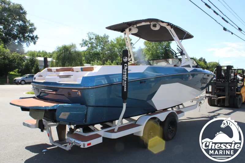 Slide: The Image of 2025 Axis A245 boat on a trailer, blue and white, with a sunshade, parked outdoors. - 5
