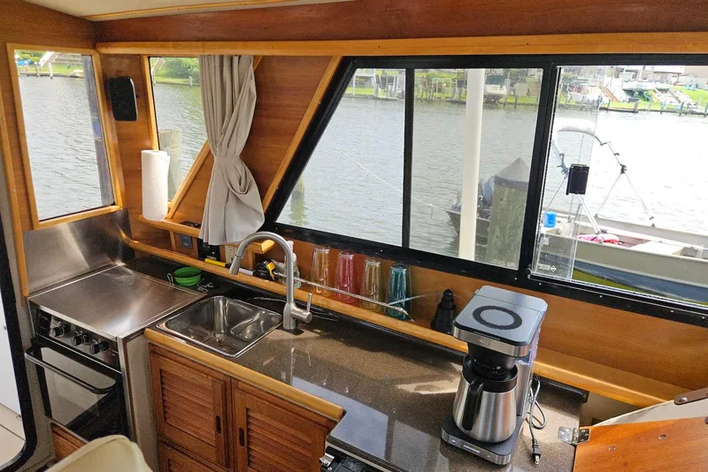 Slide: The Image of Interior of 2013 Cutwater 28 boat kitchen with sink, stove, and coffee maker by window. - 15