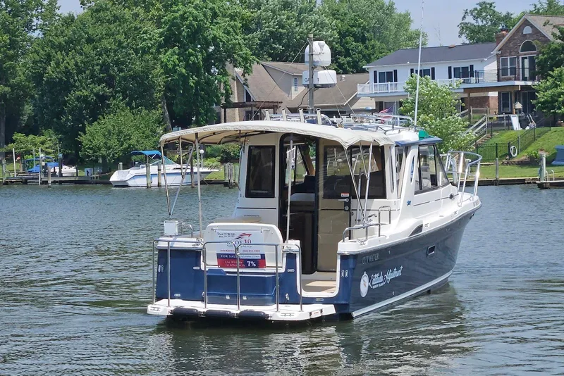 Slide: The Image of 2013 Cutwater 28 boat on a scenic waterfront with houses and greenery. - 2