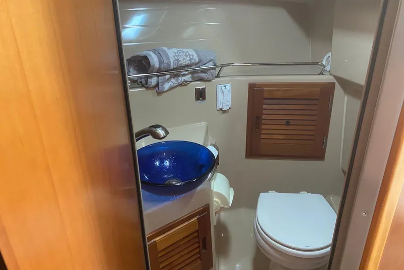 Slide: The Image of 2013 Cutwater 28 bathroom with blue glass sink and wooden cabinetry. - 27