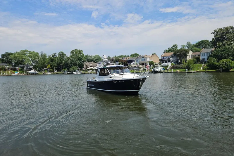 Slide: The Image of 2013 Cutwater 28 boat cruising on a scenic river with houses in the background. - 3