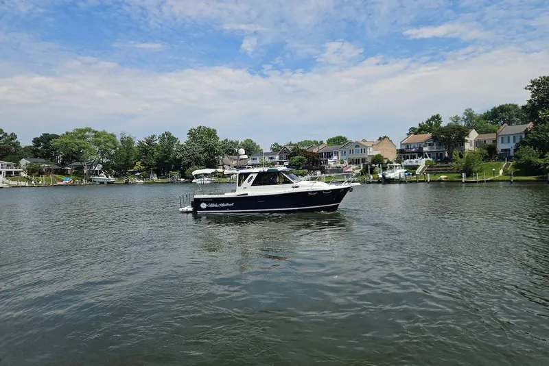 Slide: The Image of 2013 Cutwater 28 boat cruising on a scenic lake with waterfront homes. - 4