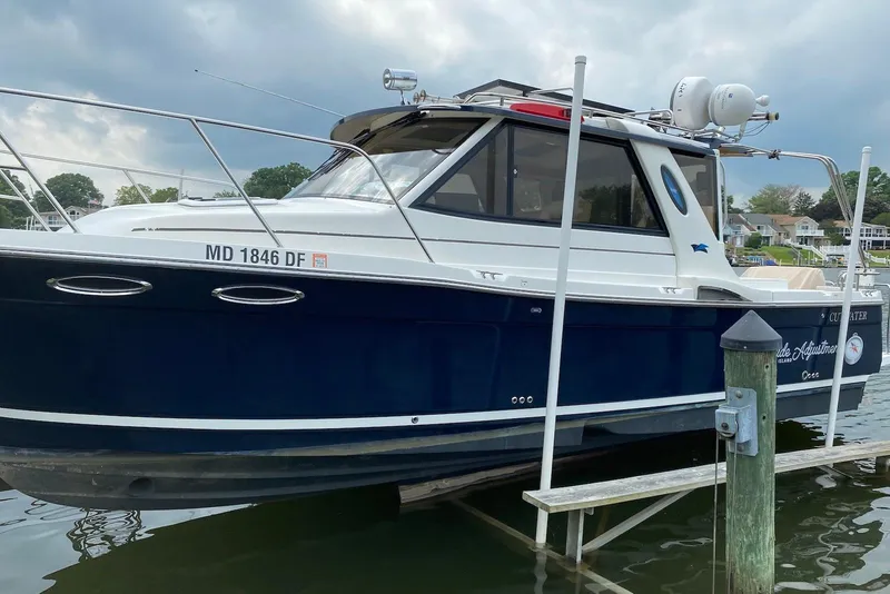 Slide: The Image of 2013 Cutwater 28 boat docked, featuring a sleek blue and white design under cloudy skies. - 9