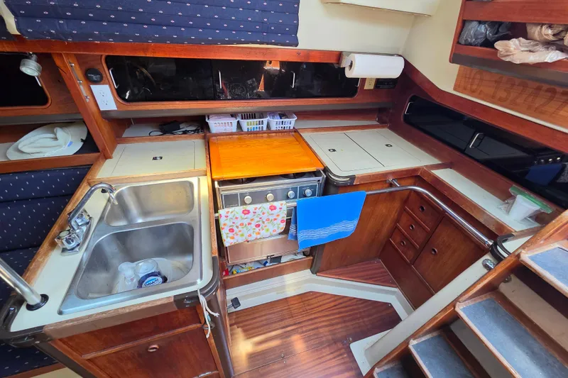 Slide: The Image of Compact kitchen area in a 1985 C&C 37 sailboat with wooden cabinetry and stainless steel sink. - 5
