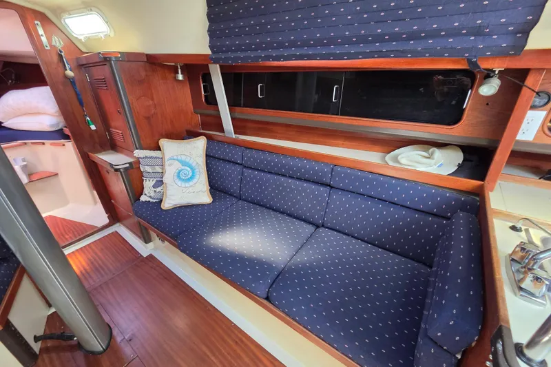 Slide: The Image of Interior of 1985 C&C 37 sailboat with blue cushioned seating and wooden accents. - 8