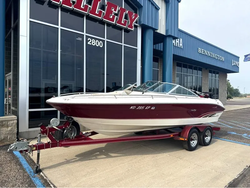 Slide: The Image of A 1996 Sea Ray 210 Signature on a trailer parked in front of a building. - 2
