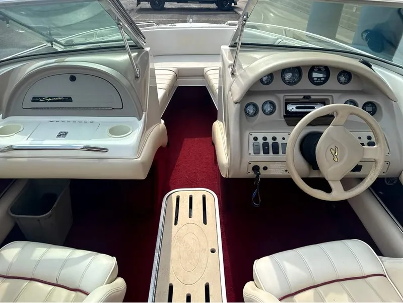Slide: The Image of The image shows the cockpit of a 1996 Sea Ray 210 Signature boat with cream seats and red carpet. - 14