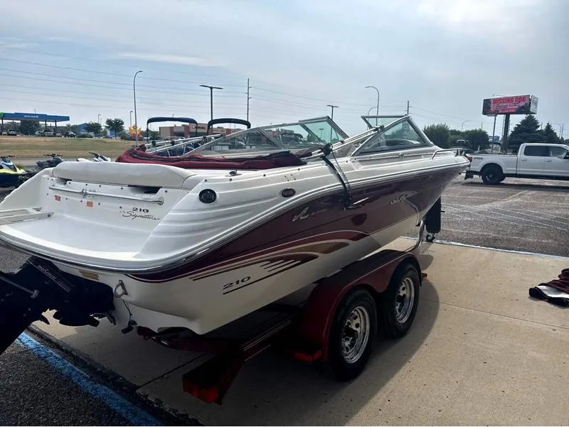 Slide: The Image of A white and red 1996 Sea Ray 210 Signature boat on a trailer in a parking lot. - 6