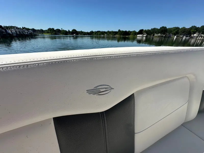 Slide: The Image of Close-up of a white and gray boat seat with a logo, in front of a calm lake. - 15