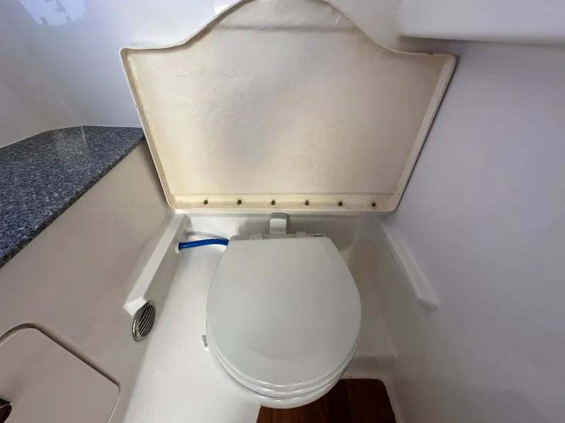 Slide: The Image of The image shows a toilet in a boat bathroom with white walls and a blue countertop. - 41