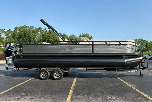 The Image of 2024 Regency 250 DL3 pontoon boat on trailer in parking lot. - 0