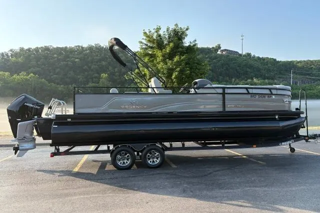 Slide: The Image of 2024 Regency 250 DL3 pontoon boat parked on a trailer in a scenic outdoor setting. - 1