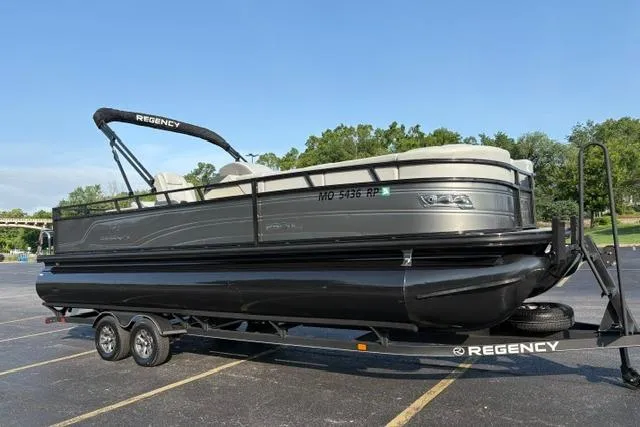 Slide: The Image of 2024 Regency 250 DL3 pontoon boat on trailer in parking lot, side view. - 3