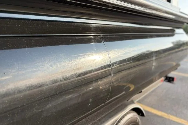 Slide: The Image of Close-up of a 2024 Regency 250 DL3 boat exterior with reflective black finish. - 44