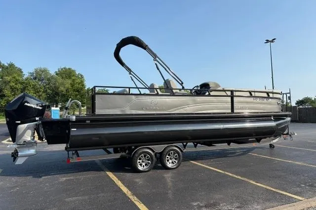Slide: The Image of 2024 Regency 250 DL3 pontoon boat on trailer in parking lot, sunny day. - 5
