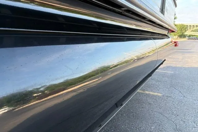 Slide: The Image of 2024 Regency 250 DL3 boat side view with sleek, reflective black finish. - 52
