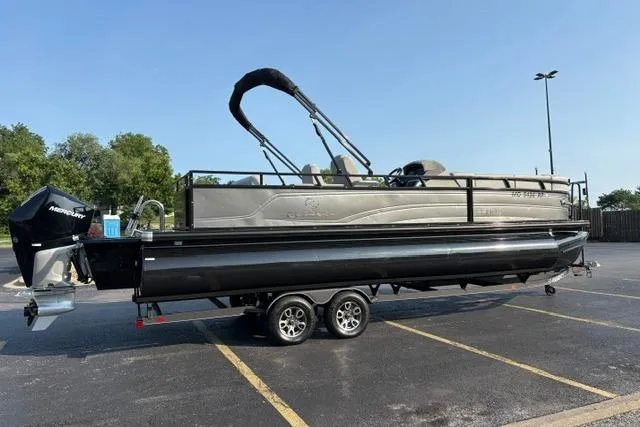 Slide: The Image of 2024 Regency 250 DL3 pontoon boat on trailer in parking lot, sunny day. - 6