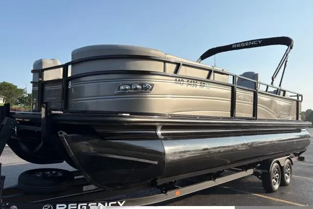 Slide: The Image of 2024 Regency 250 DL3 pontoon boat on trailer, sleek design, outdoor setting. - 9