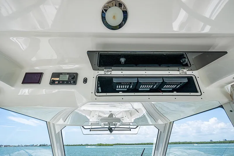 Slide: The Image of 2022 Boston Whaler 420 Outrage helm electronics compartment with open storage and control panel. - 12