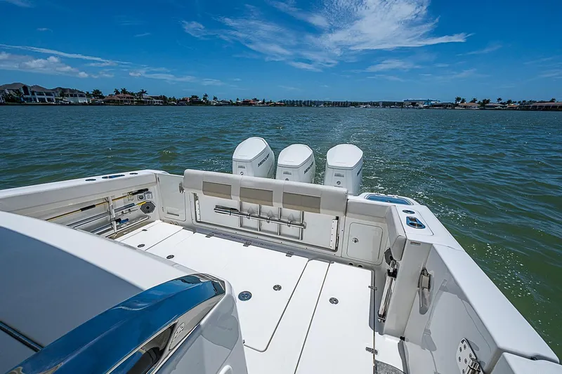 Slide: The Image of 2022 Boston Whaler 420 Outrage boat on water, showcasing spacious deck and triple engines. - 16