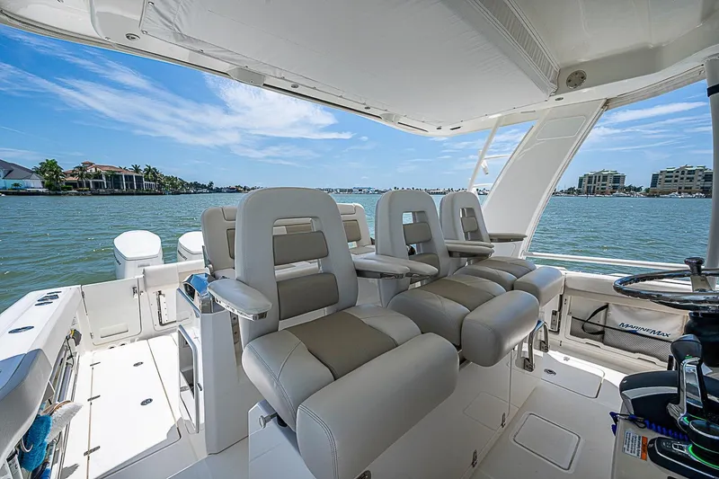 Slide: The Image of 2022 Boston Whaler 420 Outrage boat interior with luxurious seating and scenic waterfront view. - 8