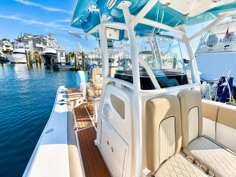 Slide: The Image of A 2018 Sea Fox 266 Commander with beige upholstery and blue canopy, docked at a marina. - 18