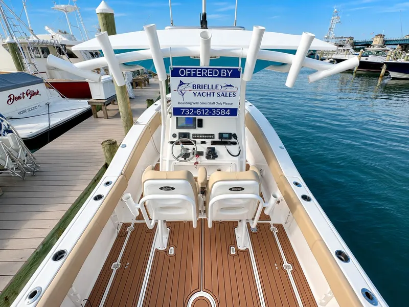 Slide: The Image of The image shows a 2018 Sea Fox 266 Commander boat at a dock. It features an open cockpit with two seats and a helm. A sign with contact details is visible. - 27