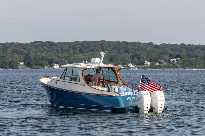 Slide: The Image of 2022 Hinckley 35 boat cruising on water with American flag, scenic shoreline background. - 4