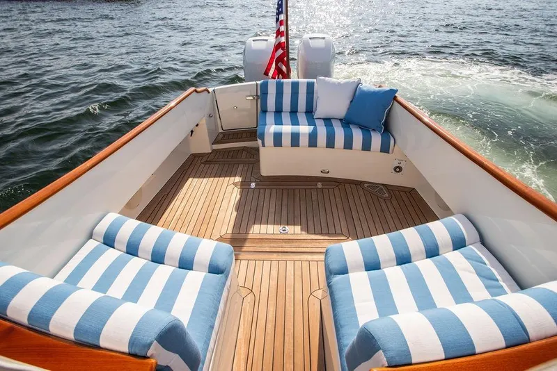 Slide: The Image of Hinckley 35 boat interior with striped seating, wooden deck, and American flag, 2022 model. - 20