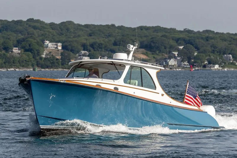 Slide: The Image of 2022 Hinckley 35 boat cruising on water with American flag, scenic shoreline background. - 5