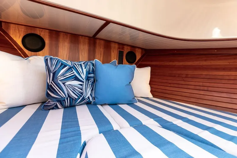Slide: The Image of Interior of 2022 Hinckley 35 boat with striped bedding and decorative pillows. - 3