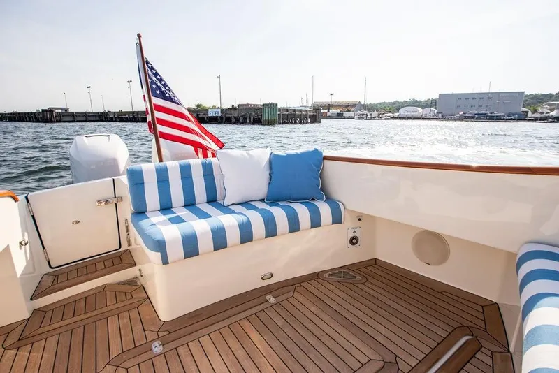 Slide: The Image of Hinckley 35 yacht interior with striped seating, American flag, and waterfront view, 2022 model. - 21