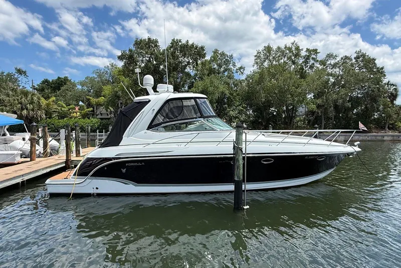 The Image of 2008 Formula 37 Performance Cruiser docked on a sunny day, surrounded by lush greenery. - 1