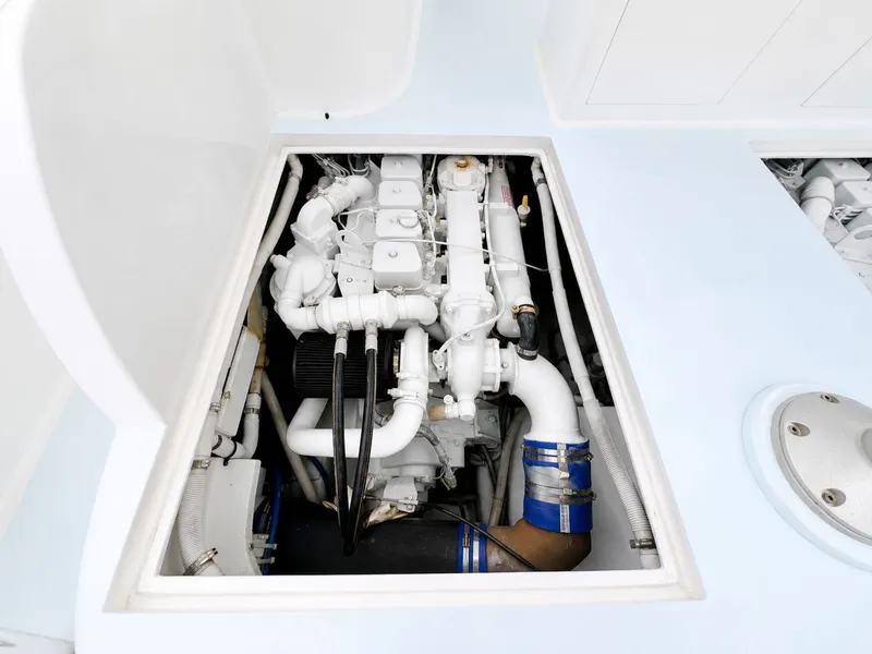 Slide: The Image of A clean engine compartment with a white engine and blue hoses in a boat. - 27