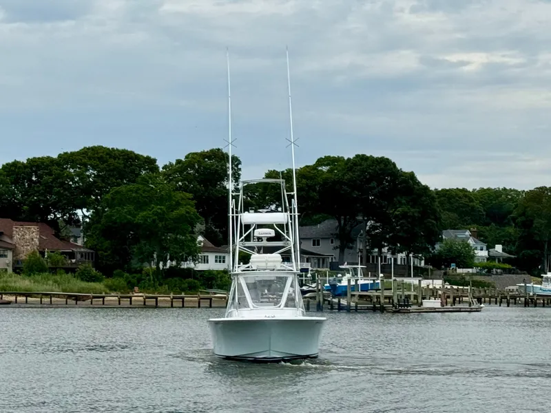 Slide: The Image of A 1992 L&H 33 boat on calm water, surrounded by houses and trees. - 2