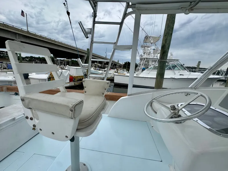 Slide: The Image of A helm station with a white captain's chair and steering wheel on a boat. - 23