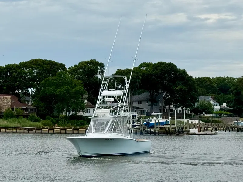 Slide: The Image of A 1992 L&H 33 boat on calm water, surrounded by trees and houses. - 3