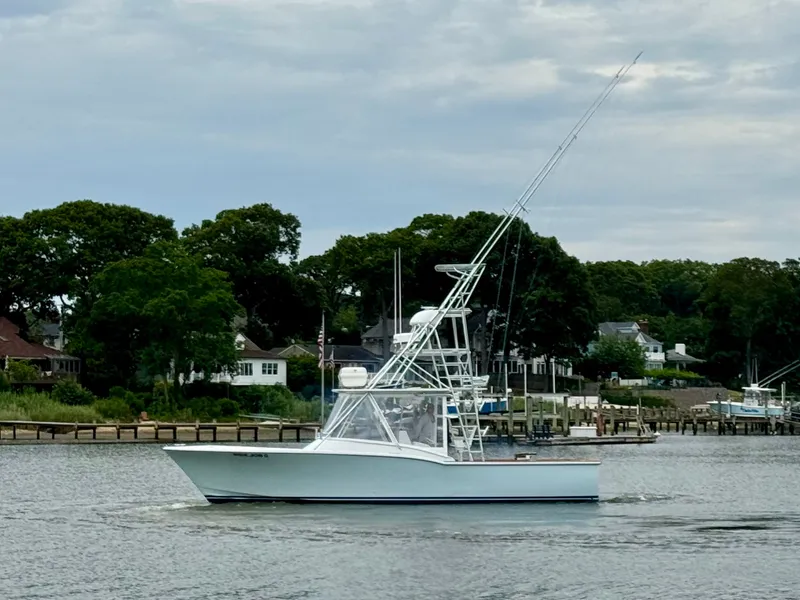 Slide: The Image of A 1992 L&H 33 boat on calm water, surrounded by trees and houses. - 4