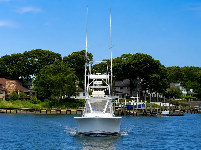 Slide: The Image of A 1992 L&H 33 boat on calm water, surrounded by houses and trees. - 2