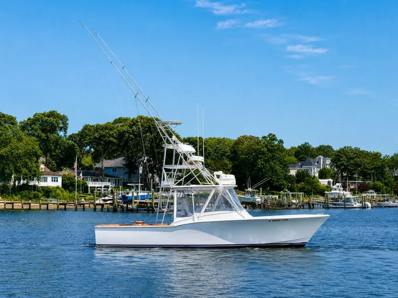The Image of A 1992 L&H 33 boat on calm water with houses in the background. - 0
