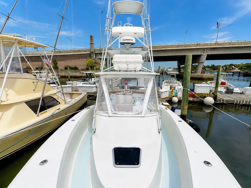 Slide: The Image of A 1992 L&H 33 boat docked in a marina. It features a tall helm and is surrounded by other boats. - 14