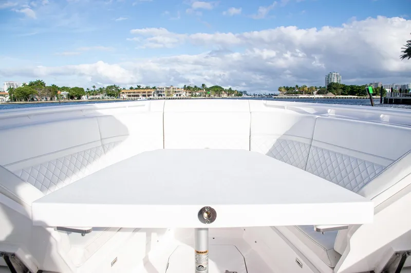 Slide: The Image of Luxurious 2021 Intrepid boat interior with white seating and table, overlooking scenic waterfront. - 14