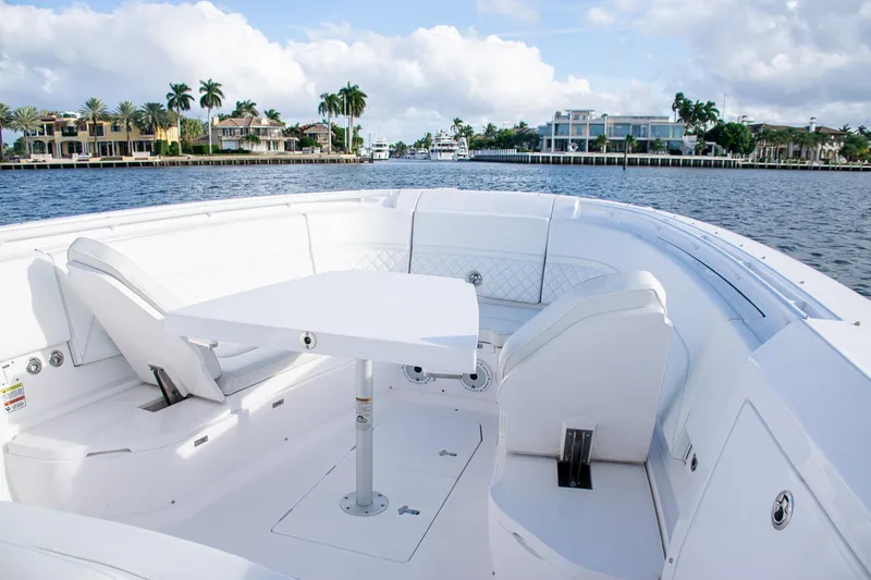 Slide: The Image of Luxurious 2021 Intrepid boat interior with white seating and table, docked near waterfront homes. - 10