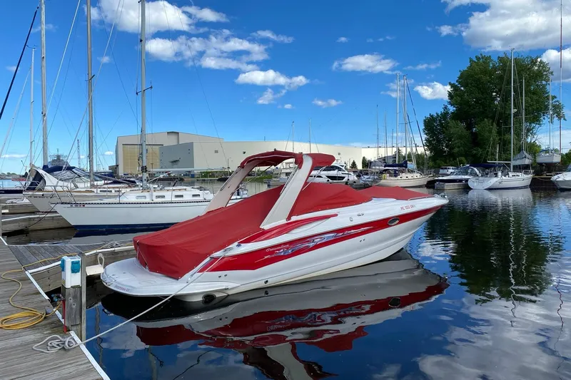 Slide: The Image of 2008 Crownline 320 LS boat with red cover docked at marina under blue sky. - 2